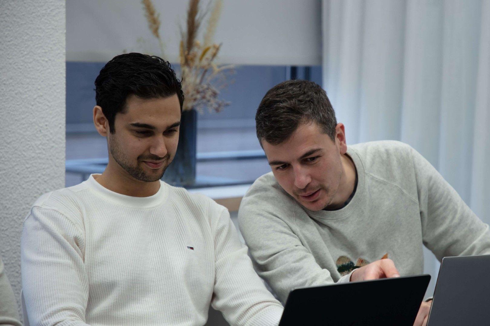 Robert en Ramon bespreken samen een project op een laptop
