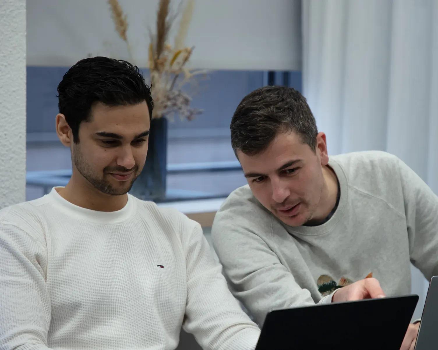 Robert en Ramon bespreken samen een project op een laptop