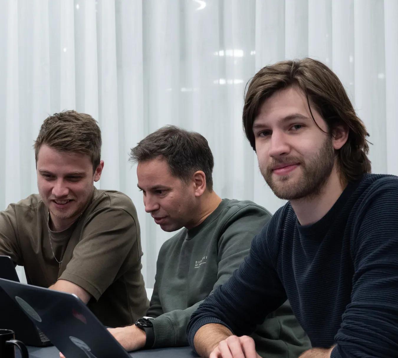 Thomas en Jeroen werken met een collega samen achter hun laptops